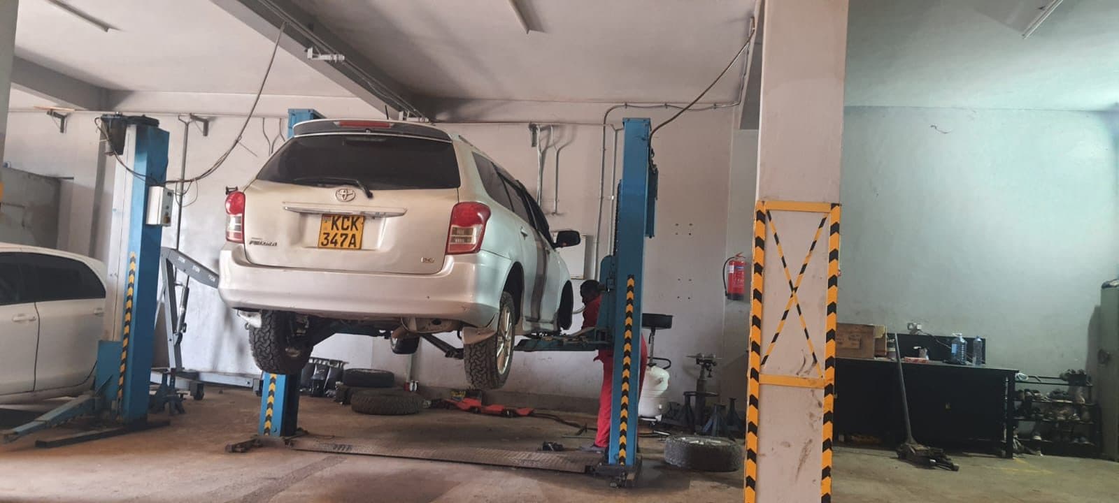 Toyota Fielder raised on a lift with a mechanic working underneath