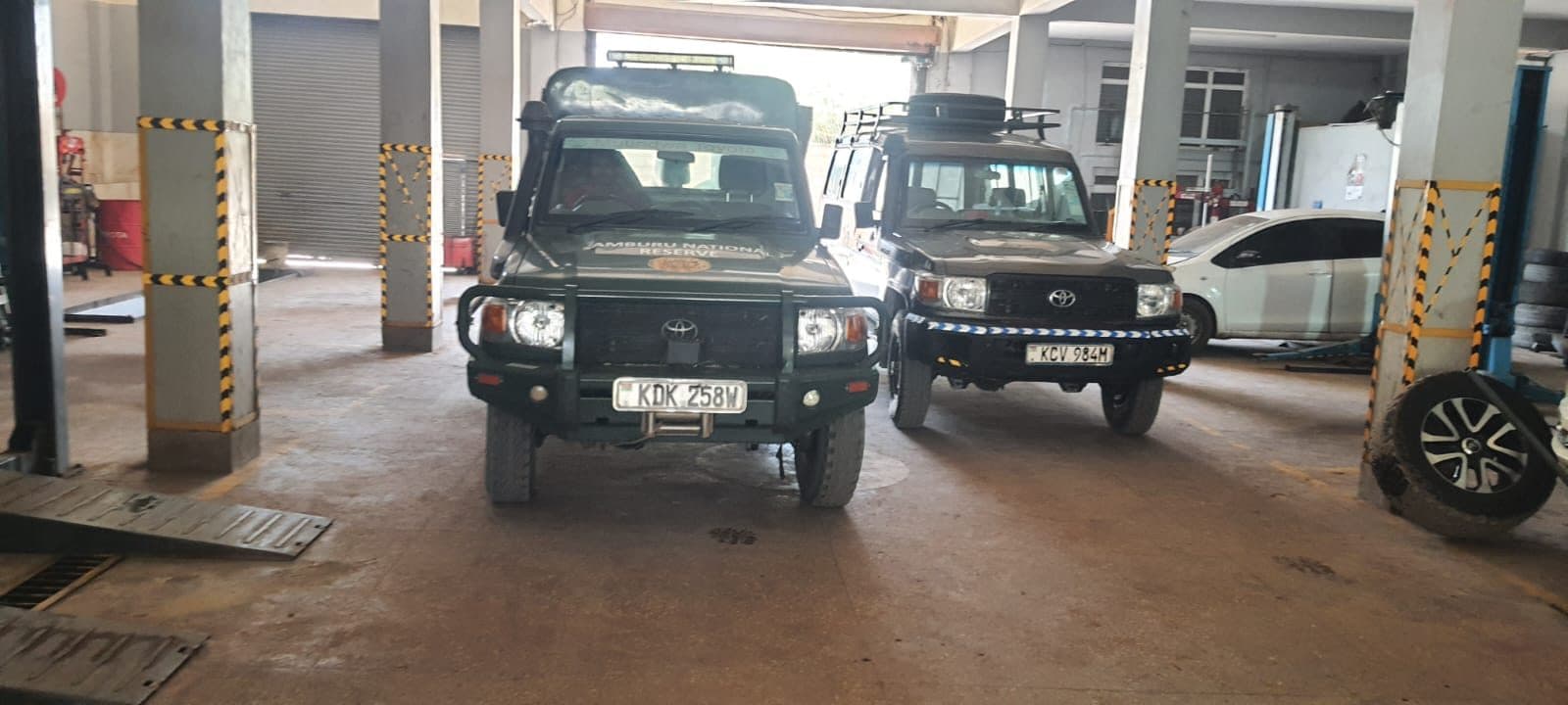 Two Toyota Land Cruisers parked front-on inside the workshop